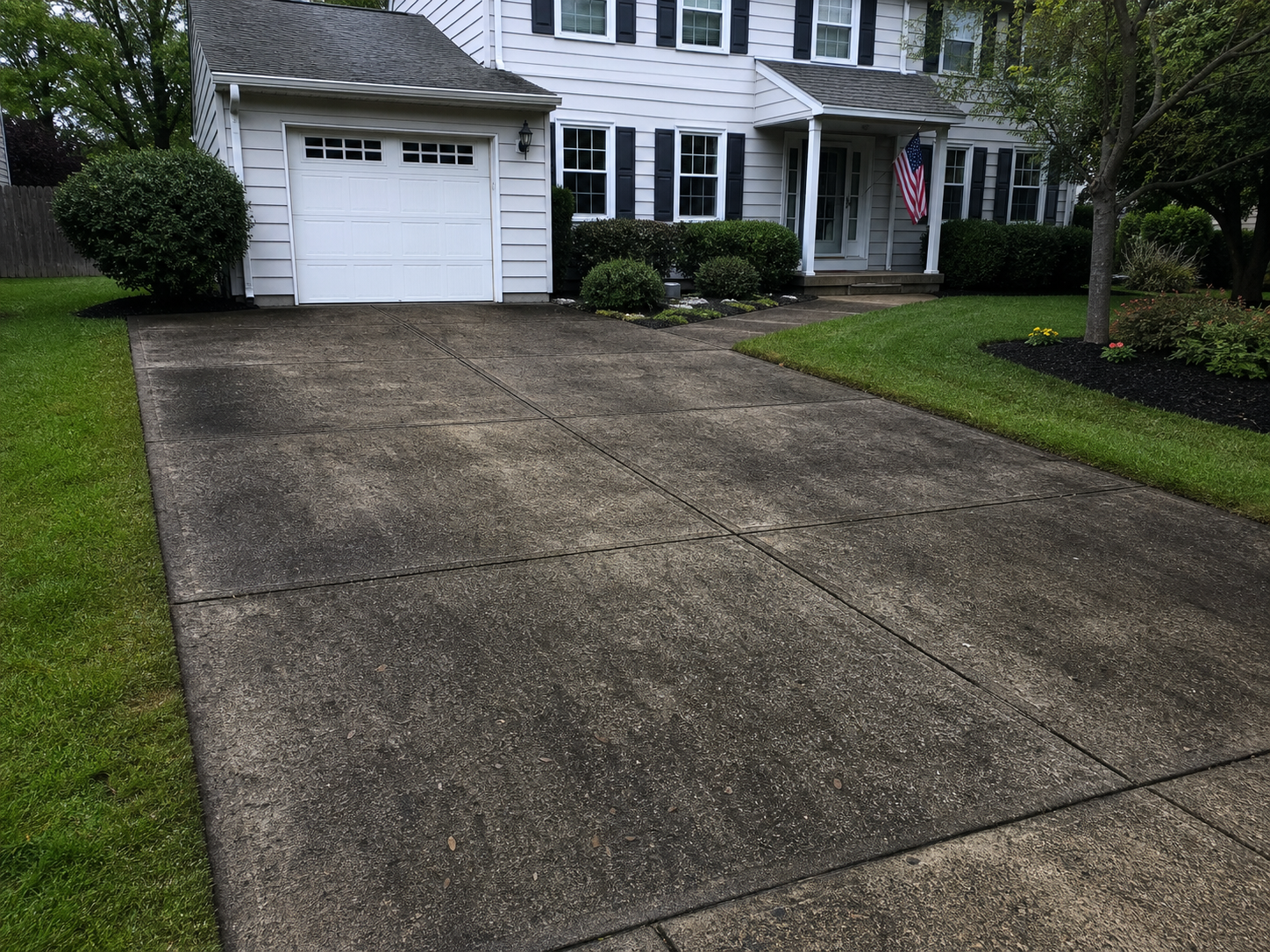 Same driveway before pressure washing with heavy grime and staining